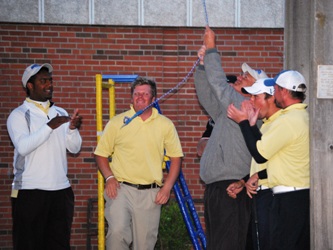 Coach Jon Daniels and the golf team ring the victory bell upon returning to campus Tuesday night.